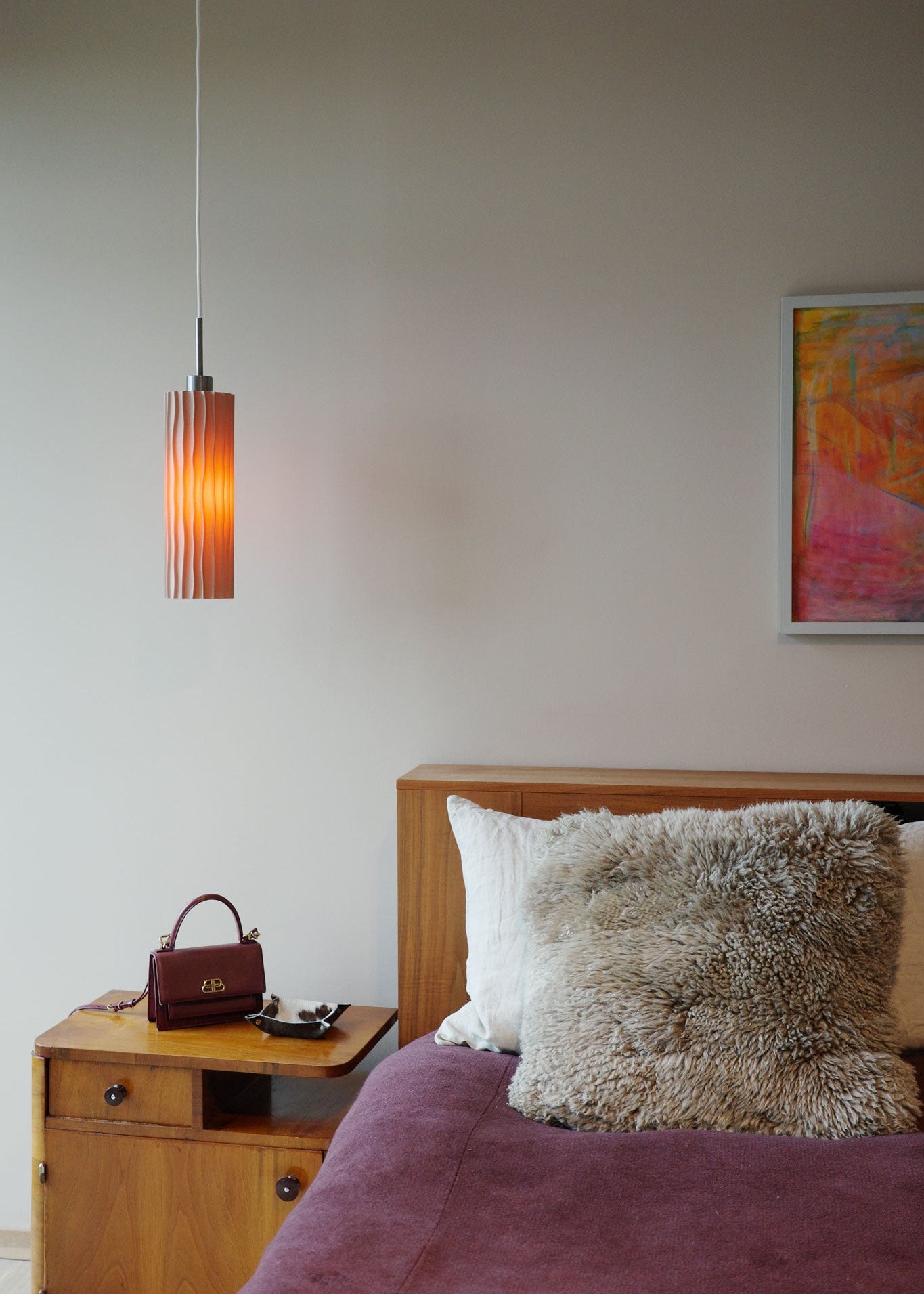 Kakta pendant in the colour linen hanging by a bed